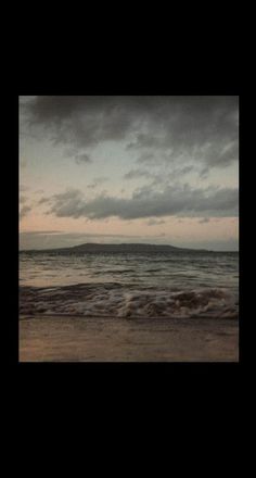 a person walking on the beach at sunset with an umbrella in hand and waves coming toward them