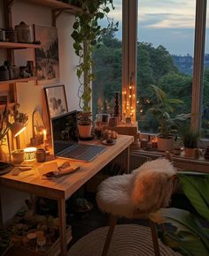 a desk with a laptop on it in front of a window filled with plants and candles