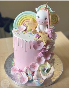 a pink cake decorated with unicorns and flowers