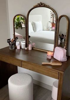 a vanity table with a mirror, brush and other items on it in front of a bed