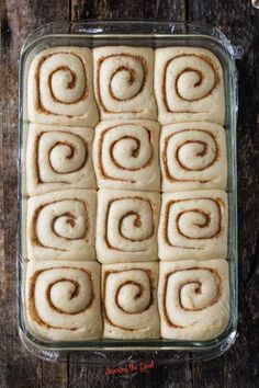 a pan filled with cinnamon rolls on top of a wooden table