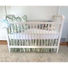 a white crib with green and white bedding