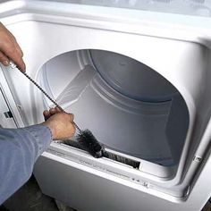 a person using a brush to clean an appliance in a washer machine