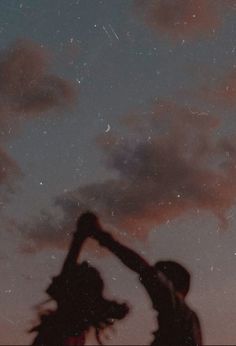 two people reaching up into the sky at night