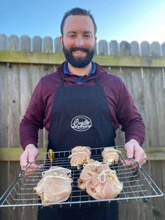 a man in an apron holding some meat on a grill