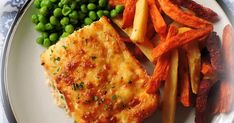 a white plate topped with fish and veggies next to fries on top of a table