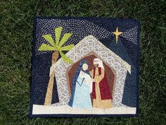 a quilted nativity scene with the birth of jesus and mary, on green grass