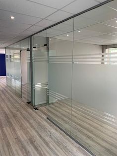 an empty office with glass walls and wood flooring