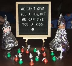 some tin foil wrapped elves are standing in front of a sign that says we can't give you a hug, but we can give you a kiss