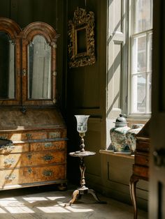 an old wooden dresser sitting in front of a window next to a table with a vase on it