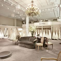 a room filled with lots of white dresses and chandelier hanging from the ceiling