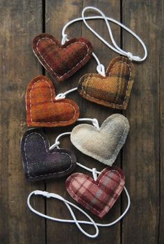 five heart shaped ornaments hanging from strings on a wooden surface with string attached to them