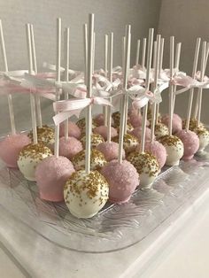 cake pops are arranged on a clear plate with pink and gold sprinkles