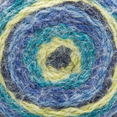 blue, yellow and green yarn is spinning in a circular pattern on top of each other