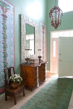 a room with a dresser, mirror and lamp on the wall next to a rug