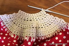 a red and white polka dot dress with a crochet hook next to it