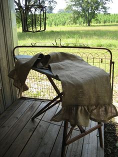 an ironing board with a blanket on it sitting on a porch next to a tree