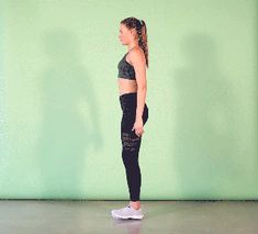 a woman standing in front of a green wall wearing black leggings and sports bra