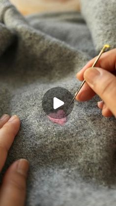 a person is using a needle to stitch something on the fabric with their thumbnails