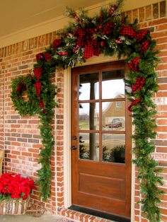 the front door is decorated for christmas with red poinsettis and greenery