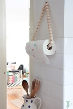 a roll of toilet paper hanging on the wall next to wooden spoons and utensils