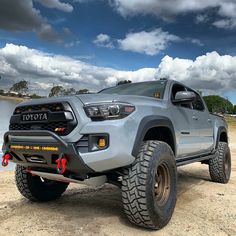 a gray toyota truck parked on top of a sandy beach