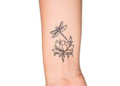 a woman's arm with a dragonfly on top of it and a flower in the middle