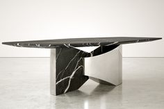 a black and white marble dining table with an oval shaped design on the top, sitting on a polished concrete floor