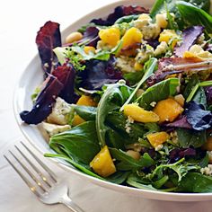 a salad with spinach, corn and feta cheese in a white bowl on a table