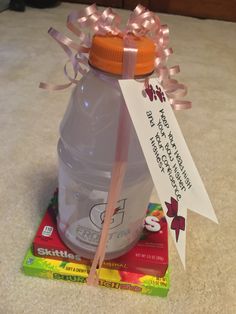 a plastic bottle with a ribbon tied around it sitting on top of some candy bars