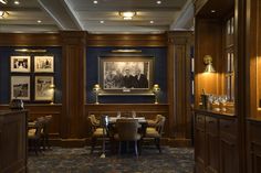 an elegant dining room with blue walls and wood paneling, along with pictures on the wall