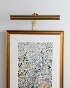 an ornate painting hangs on the wall above a gold framed art piece with a golden handle