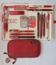 an assortment of pens and pencils in a red case