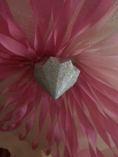 a heart shaped object is hanging from the ceiling in front of a pink and white wall