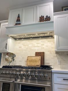 a kitchen with white cabinets and stainless steel stove top oven, range hood and wooden cutting board