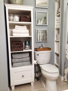 a white toilet sitting in a bathroom next to a shelf filled with towels and other items