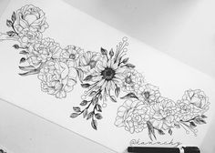 a black and white drawing of flowers on a piece of paper next to a pen