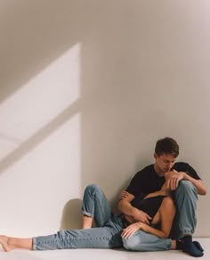 two people sitting on the floor next to each other with their arms around one another