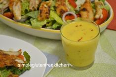 a salad with chicken and dressing next to a glass of orange juice