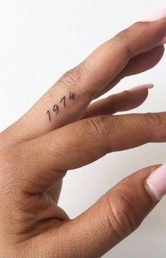 a woman's hand with a small tattoo on her left thumb and the word love written