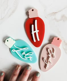 three heart shaped magnets with the word love written on them and one being held by a woman's hand