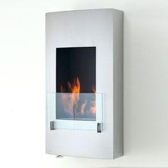 a white wall mounted fire place with flames in the glass and metal frame on it