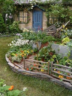 the garden is full of flowers and plants, including an old wooden fence with a blue door