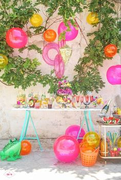 an outdoor party with balloons and decorations on the outside wall, hanging from a tree