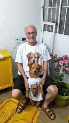 an older man sitting on the floor with two dogs wearing t - shirts that look like faces