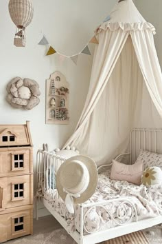 a white bed with a canopy and pillows on top of it in a child's room