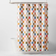 a shower curtain with multicolored squares on the outside and inside, hanging from a metal rod