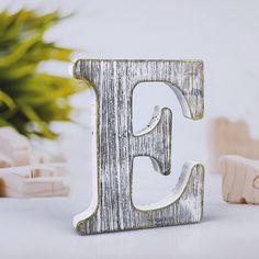 the letter e is made out of wood and sits on a table next to other wooden toys