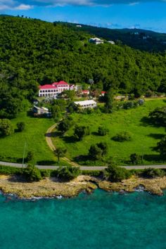 an aerial view of a large house on the side of a hill next to water