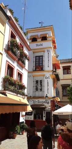 people are walking down the street in front of buildings with balconies on them